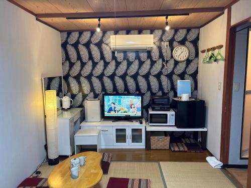 a living room with a tv on a wall at hostel sunflower202 in Osaka