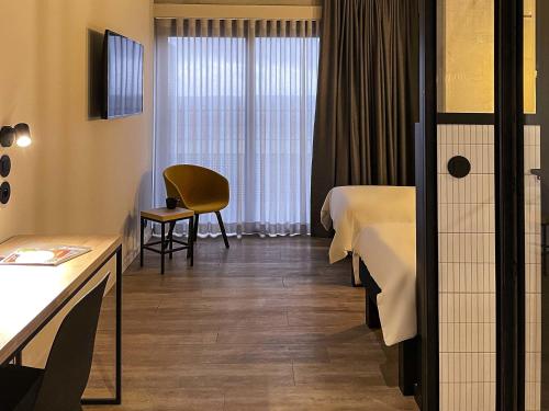 a hotel room with two beds and a chair at ibis Styles Namur in Namur