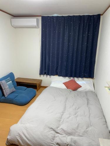 a bedroom with a bed and a blue curtain at Akane Craft Inn in Hachinohe