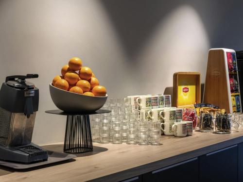 a bowl of oranges sitting on a counter with drinks at ibis Styles Namur in Namur