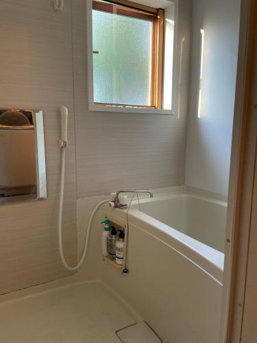 a bathroom with a bath tub and a window at Akane Craft Inn in Hachinohe