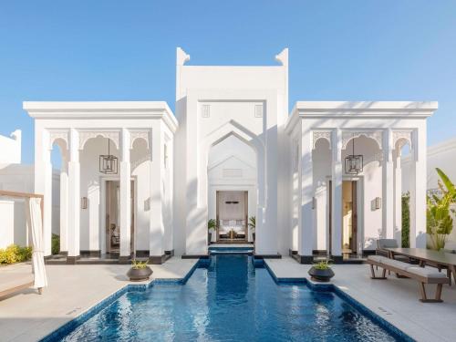 a white building with a pool in front of it at Raffles Al Areen Palace Bahrain in Manama