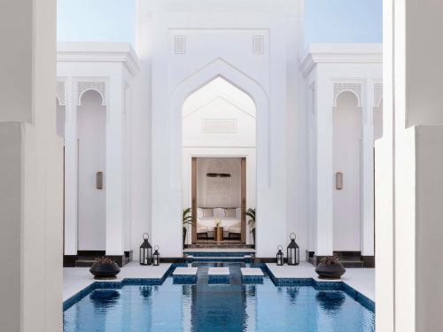 a large white building with a pool in the middle at Raffles Al Areen Palace Bahrain in Manama