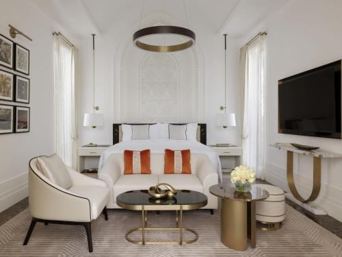 a bedroom with a bed and a couch and a tv at Raffles Al Areen Palace Bahrain in Manama