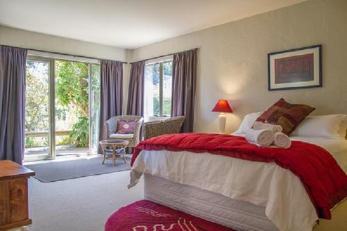 a bedroom with a large bed with a red blanket at Taigh na Mara Bed and Breakfast in Whitianga