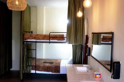 two bunk beds in a room with a sink and a mirror at Tide and Tribe hostel in Kuta Lombok
