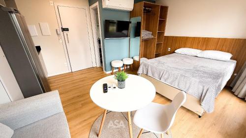 um pequeno quarto com uma cama, uma mesa e cadeiras em ASA | Loft UP 309 | Lado da FURB | Oktoberfest em Blumenau