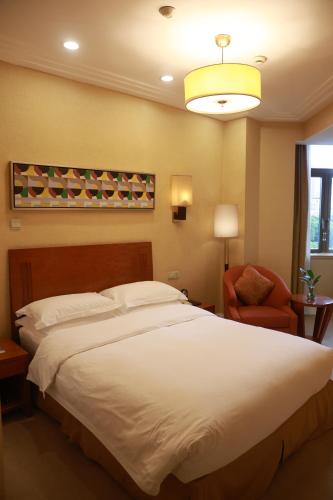 a bedroom with a large white bed and a chair at Broadway Mansions Hotel - On the Bund - Journey Through Time Old Shanghai Republic Dreams in Shanghai