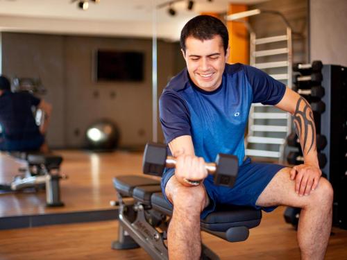 a man sitting on a chair in a gym at Novotel Criciuma in Criciúma