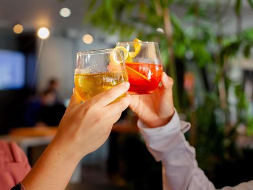 a person holding two wine glasses in their hands at Novotel Criciuma in Criciúma