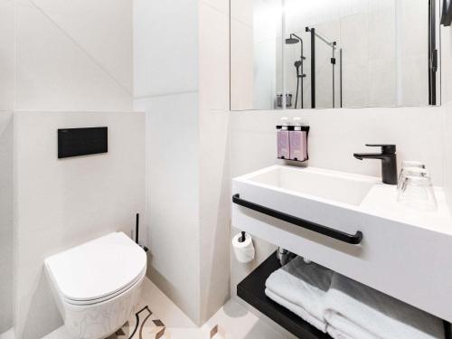 a white bathroom with a toilet and a sink at TRIBE Riga City Centre in Rīga