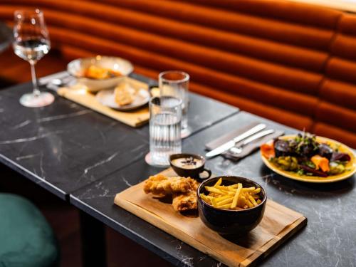 a table with plates of food and glasses of wine at TRIBE Riga City Centre in Rīga