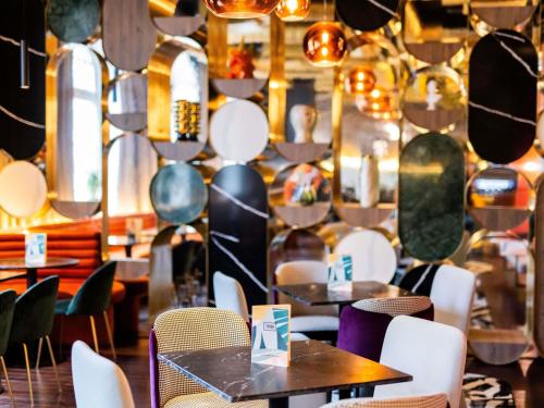 a restaurant with tables and chairs and a wall with mirrors at TRIBE Riga City Centre in Rīga