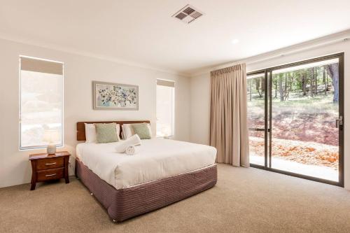 una camera da letto con un letto grande e una grande finestra di Wildgreen Villa - Lakeside Hideaway in Winery Estate a Yallingup Siding