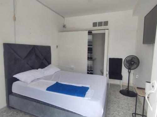 a bedroom with a white bed and a fan at Hospedaje ASL Home La Estancia in Yumbo