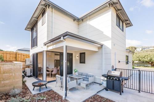 a white house with a patio with a grill at Yallingup Lagoon Beach House in Yallingup