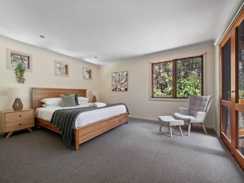 ein Schlafzimmer mit einem Bett und einem Stuhl und Fenstern in der Unterkunft Woodland Retreat - Nature Lovers' Ultimate Escape in Margaret River Town