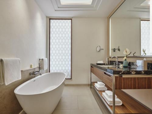 a bathroom with a tub and a large mirror at Fairmont Taghazout Bay in Taghazout