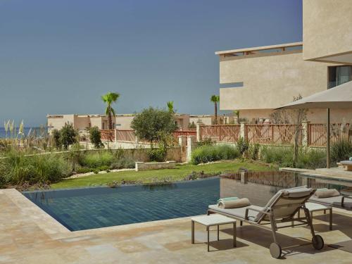 a house with a swimming pool and a patio with a chair at Fairmont Taghazout Bay in Taghazout