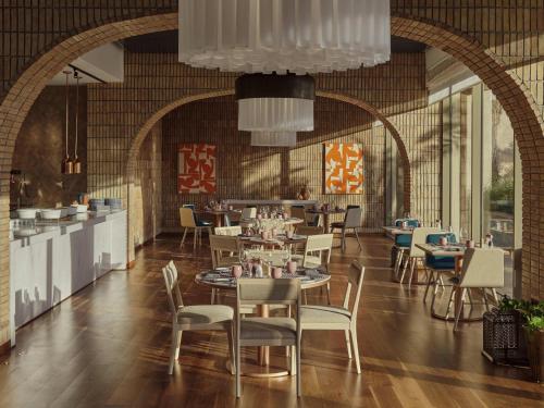 a restaurant with tables and chairs in a room at Fairmont Taghazout Bay in Taghazout