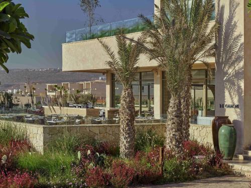 a building with palm trees in front of it at Fairmont Taghazout Bay in Taghazout