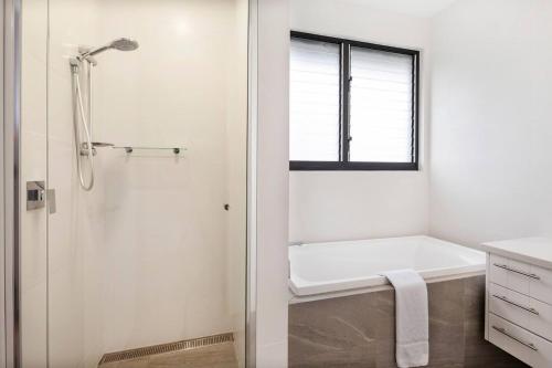 a white bathroom with a tub and a shower at Yallingup Dunes - Contemporary Coastal Comforts in Yallingup
