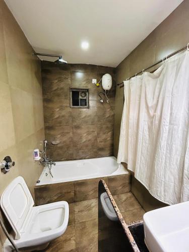 a bathroom with a tub and a toilet and a sink at HV Beach Resort in Mandvi