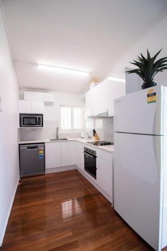 a kitchen with white cabinets and a white refrigerator at Entire New renovated 2bedrm unit next to southbank in Brisbane