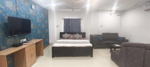 a bedroom with a bed and a tv and a couch at Hotel zova in Karīmnagar