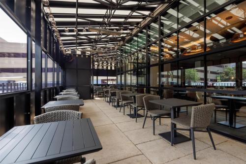 a row of tables and chairs in a restaurant with windows at Hyatt Centric Chicago Ohare in Rosemont