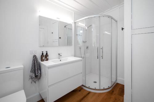 a white bathroom with a shower and a sink at Quintessential Russell Cottage in Russell