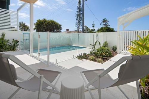 a patio with two chairs and a swimming pool at The Tropic - Dicky Beach Escape in Caloundra