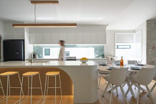 a kitchen with a island with chairs and a counter top at The Tropic - Dicky Beach Escape in Caloundra