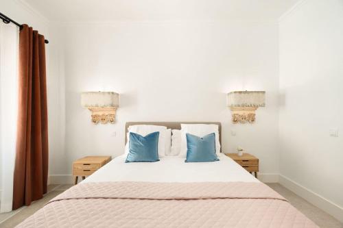 a bedroom with a white bed with blue pillows at Lagoa Vacation Home in Lagoa