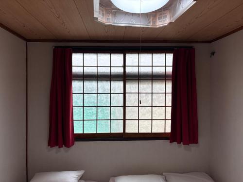 a bedroom with a window with red curtains and a bed at hostel sunflower202 in Osaka