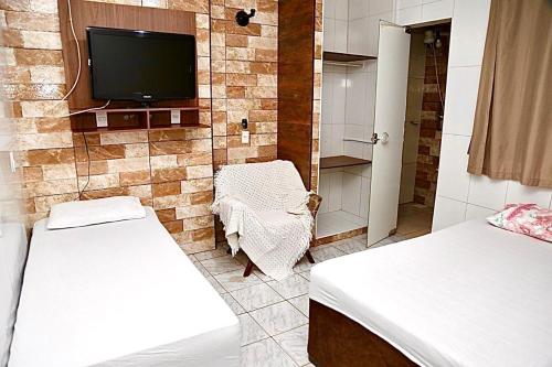 a room with two beds and a tv on a wall at Studio 01 térreo in Goiânia