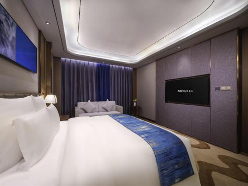 a bedroom with a large bed and a flat screen tv at Novotel Changsha International Exhibition Center in Changsha