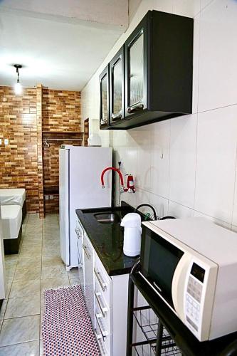 a kitchen with a microwave and a refrigerator at Studio 01 térreo in Goiânia