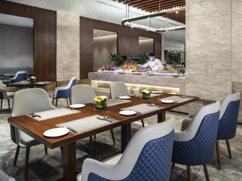 a restaurant with tables and chairs and a chef in the background at Novotel Changsha International Exhibition Center in Changsha