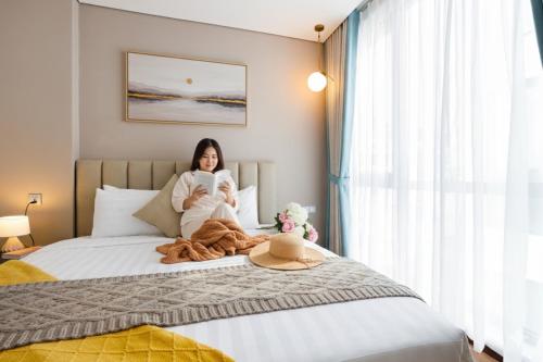a woman sitting on a bed holding a baby at Margaery Boutique Apartment & Skyon9 Rooftop Bar in Hanoi