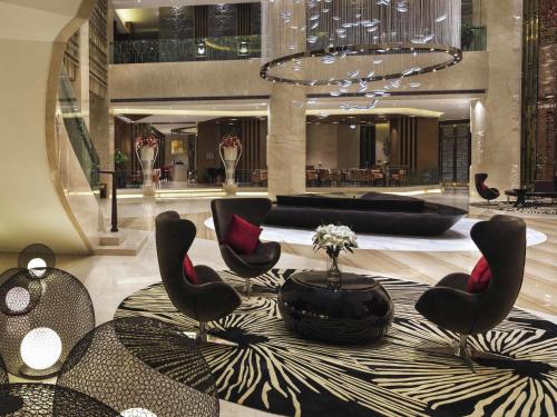 a lobby with chairs and a table in a building at Movenpick Hotel Enshi in Enshi