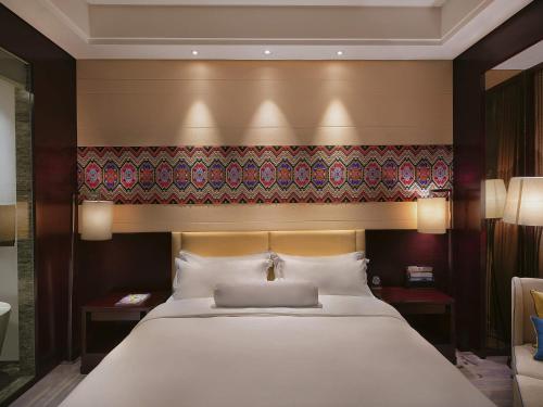a bedroom with a large white bed with a headboard at Movenpick Hotel Enshi in Enshi