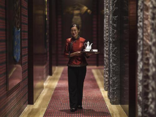 a woman walking down a hallway holding a cake at Movenpick Hotel Enshi in Enshi