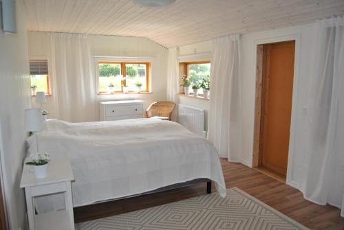 a white bedroom with a bed and a table at Orsastuguthyrning-Höglunda in Orsa