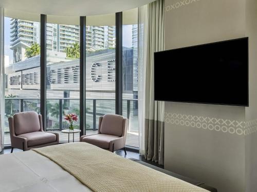 a bedroom with a flat screen tv and two chairs at SLS LUX Brickell in Miami