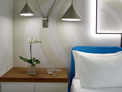 a bedroom with a blue chair and a table with a vase of flowers at Mondrian Los Angeles in Los Angeles