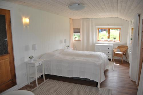 a white bedroom with a large bed and a window at Orsastuguthyrning-Höglunda in Orsa