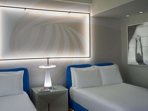 a bedroom with a bed and a lamp next to a table at Mondrian Los Angeles in Los Angeles