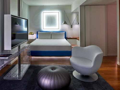 a bedroom with a bed and a chair and a television at Mondrian Los Angeles in Los Angeles