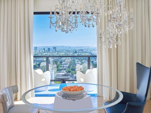 a dining room with a glass table and a chandelier at Mondrian Los Angeles in Los Angeles